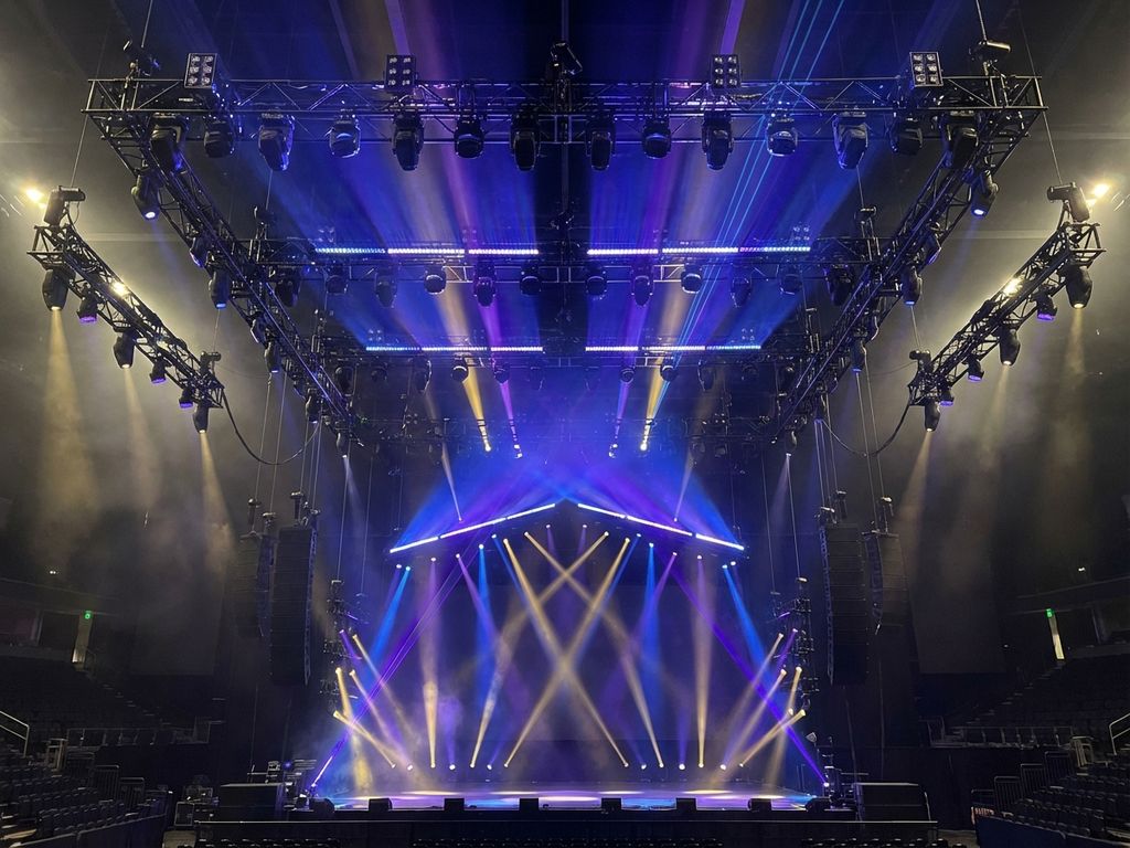 Professioneel concertpodium met uitgebreide LED-verlichting in blauw, paars en goud, gezien vanuit publieksperspectief
